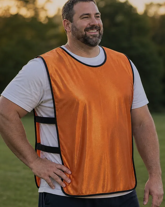 A big-and-tall adult player in an orange SportsRepublik pinnie hanging in loose folds, with slack side straps